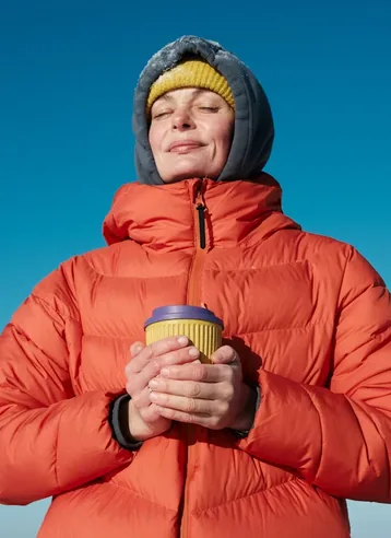 TFX client in an orange jacket holding a coffee cup